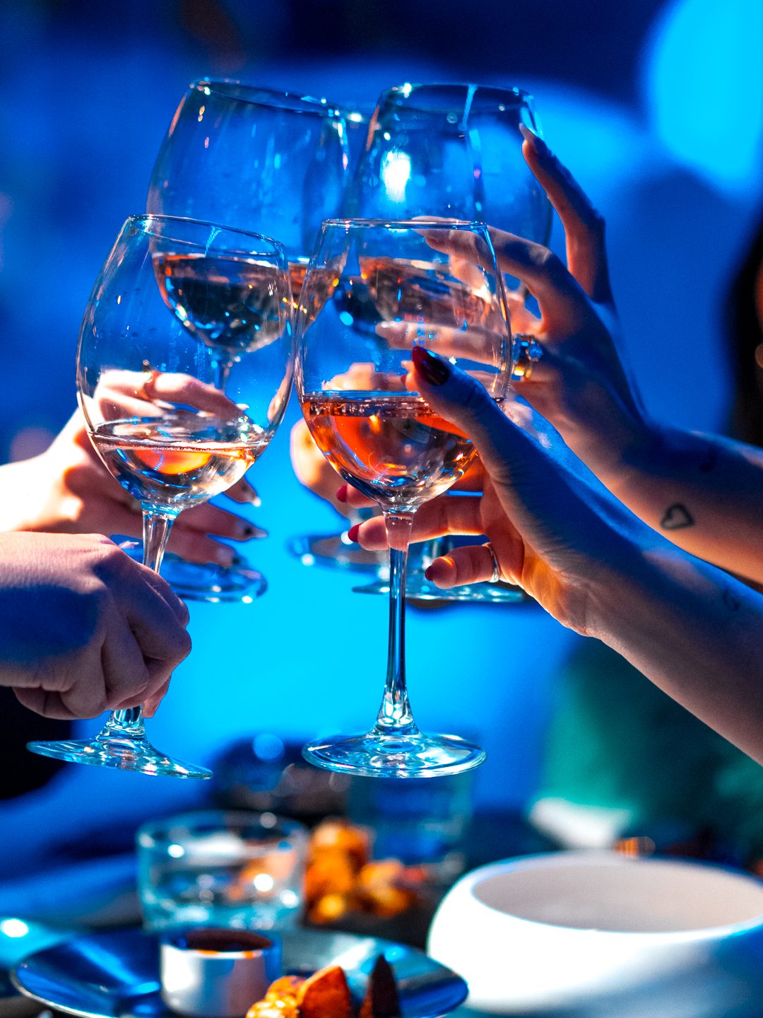 Un brindisi a tavola con i bicchieri di vino, in primo piano le mani degli ospiti