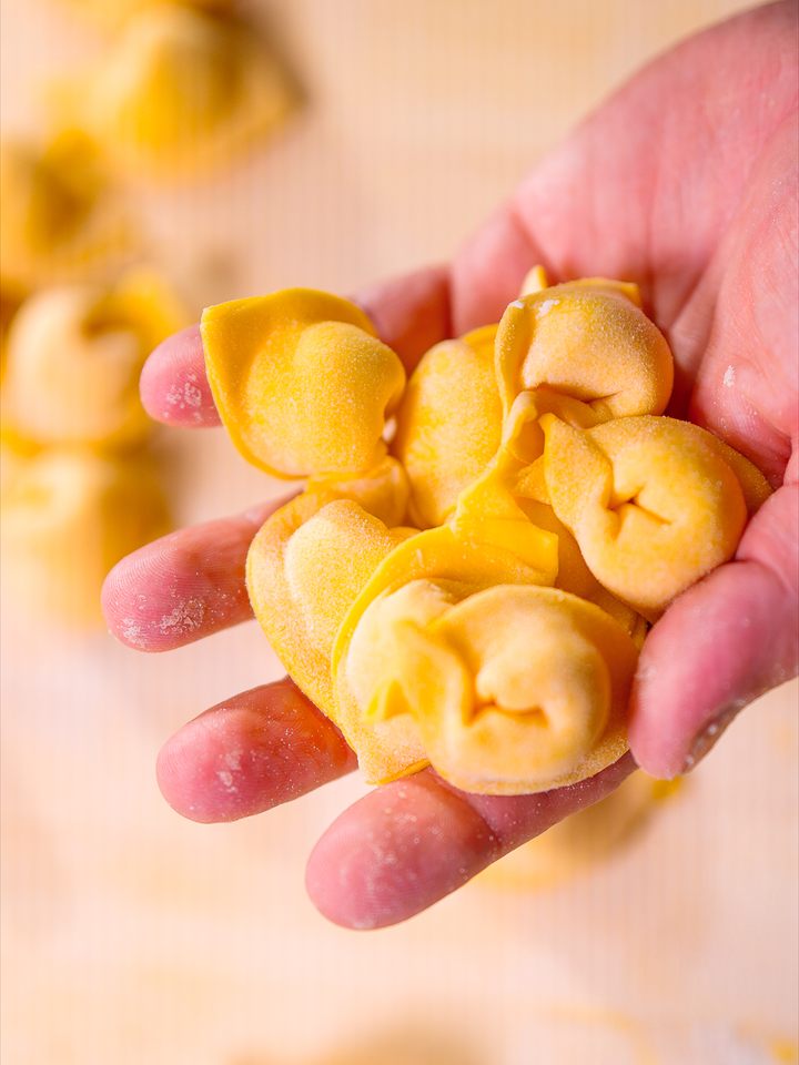 Una mano che regge della pasta fresca ripiena, appena fatta