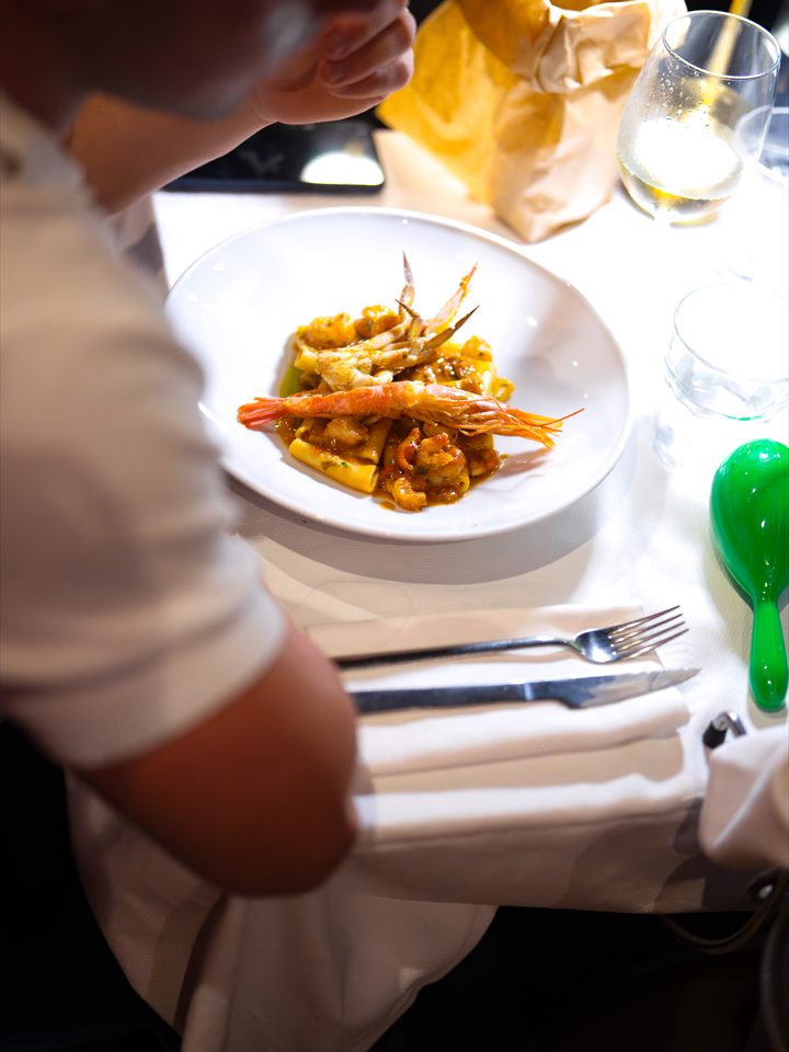 Un piatto di paccheri con gamberi su una tavola apparecchiata